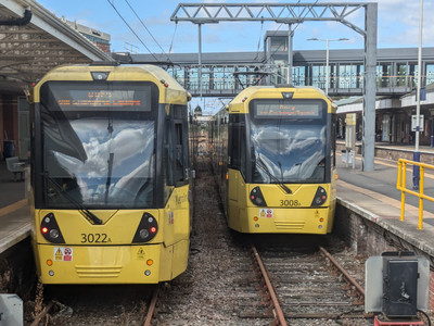 Two yellow Metrolink vehicles in platforms 1 and 2 at Altrincham